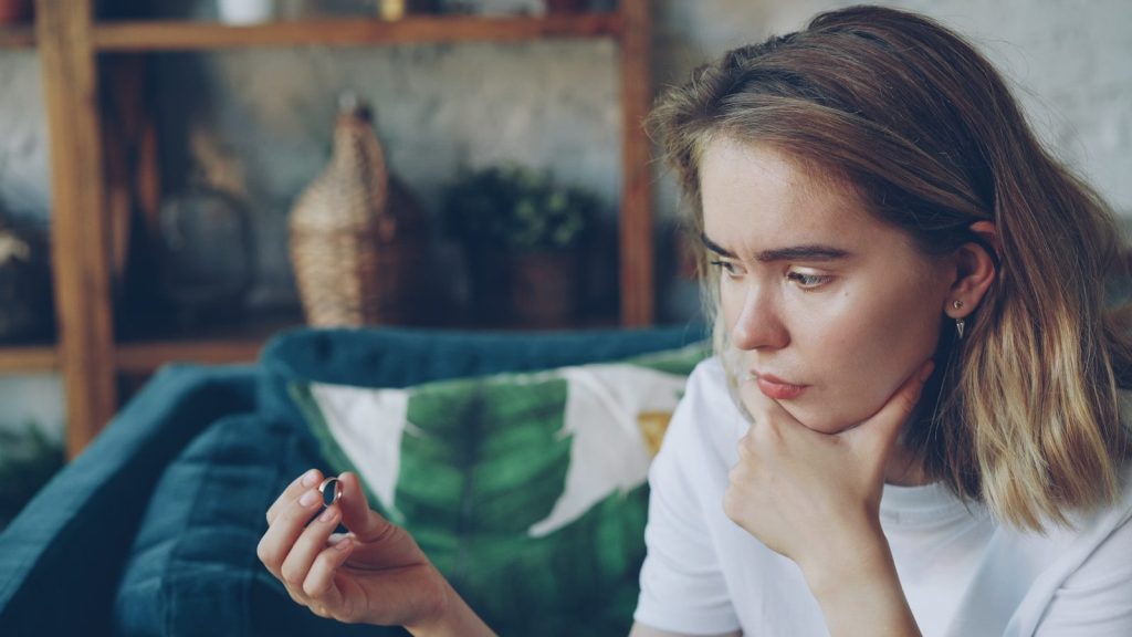 Young woman looking at a small object in her hand.